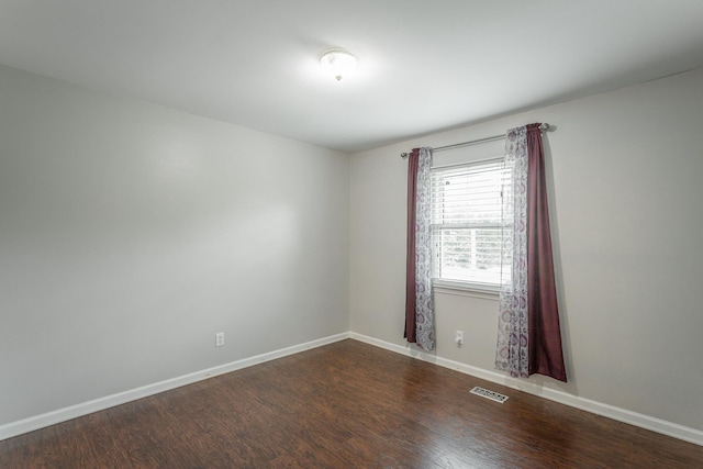 empty room featuring baseboards, visible vents, and wood finished floors