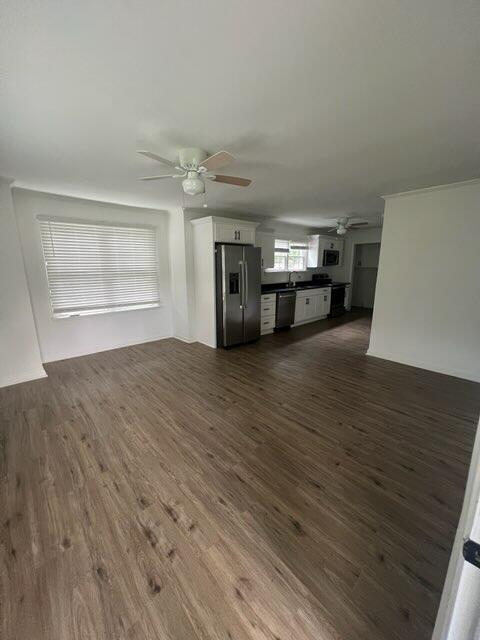 unfurnished living room featuring a sink, a ceiling fan, and dark wood-style floors
