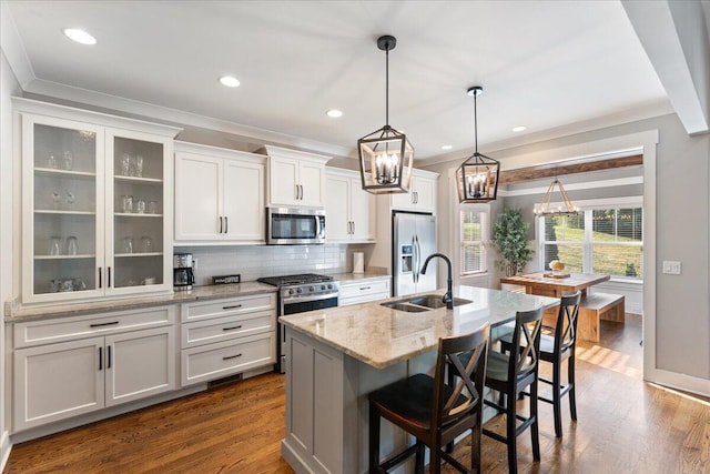 kitchen with decorative backsplash, a sink, a notable chandelier, stainless steel appliances, and white cabinetry