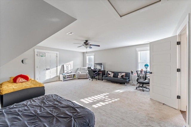carpeted bedroom with visible vents, a ceiling fan, and multiple windows