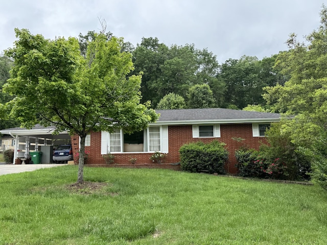 ranch-style home with brick siding, an attached carport, a front yard, and concrete driveway