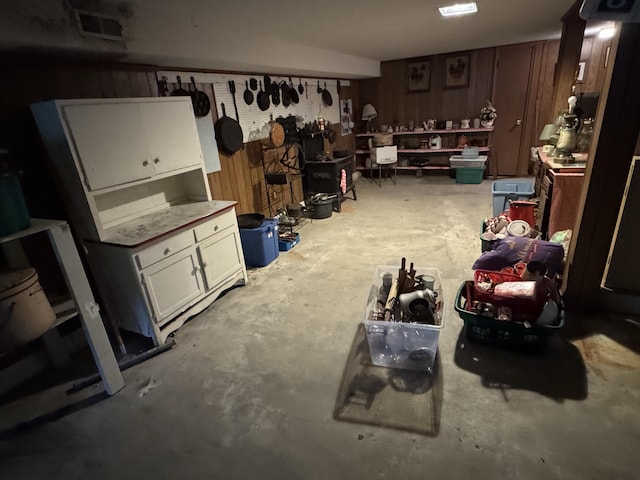 miscellaneous room featuring wooden walls, concrete floors, and visible vents