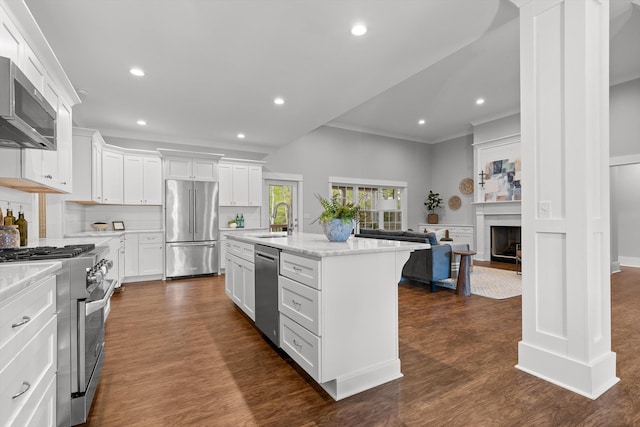 kitchen featuring ornamental molding, open floor plan, white cabinetry, a sink, and premium appliances