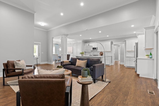living area with crown molding, ornate columns, recessed lighting, and dark wood finished floors