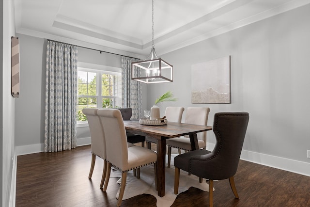 dining space with a raised ceiling, baseboards, wood finished floors, and a chandelier