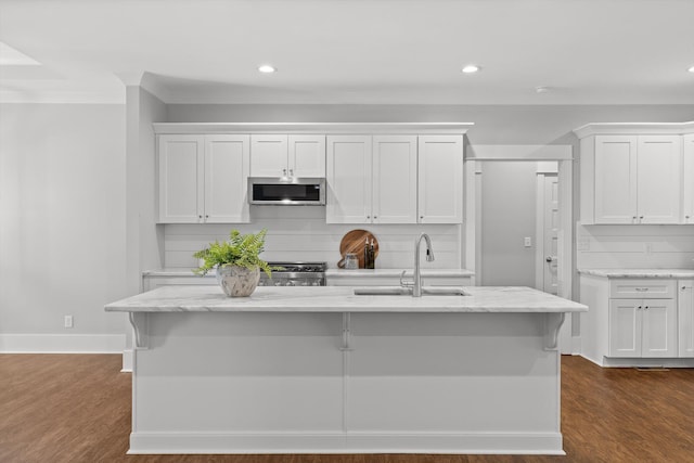kitchen with a sink, stainless steel microwave, recessed lighting, and white cabinetry