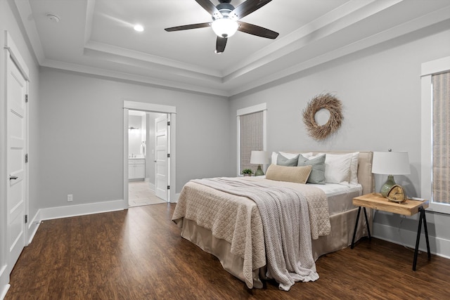bedroom with baseboards, ornamental molding, a tray ceiling, and wood finished floors