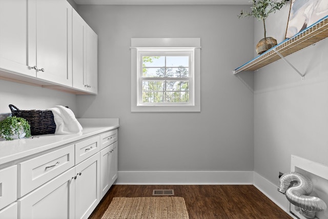 laundry area featuring cabinet space, baseboards, visible vents, and dark wood-type flooring