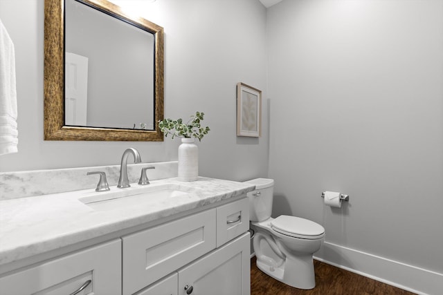 half bathroom featuring vanity, wood finished floors, and toilet
