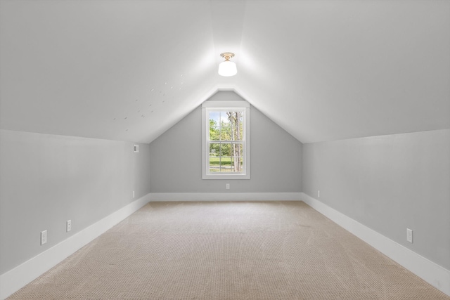 additional living space with light colored carpet, baseboards, and vaulted ceiling