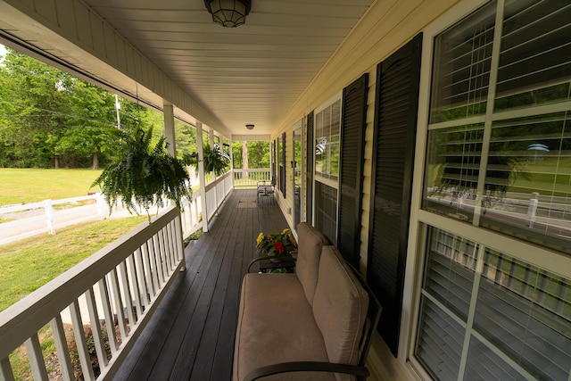 wooden terrace with a lawn and a porch