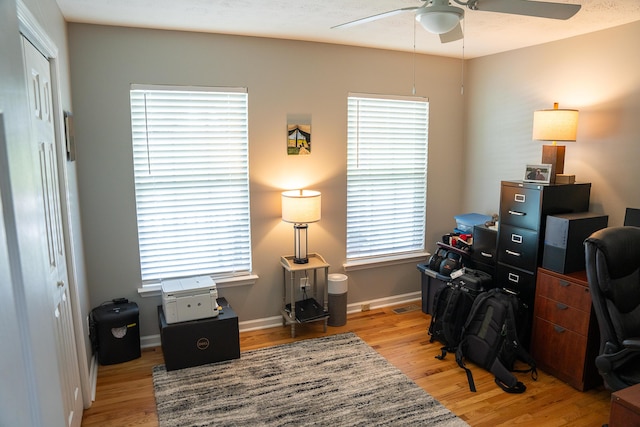 office space with light wood-style floors, a ceiling fan, and baseboards