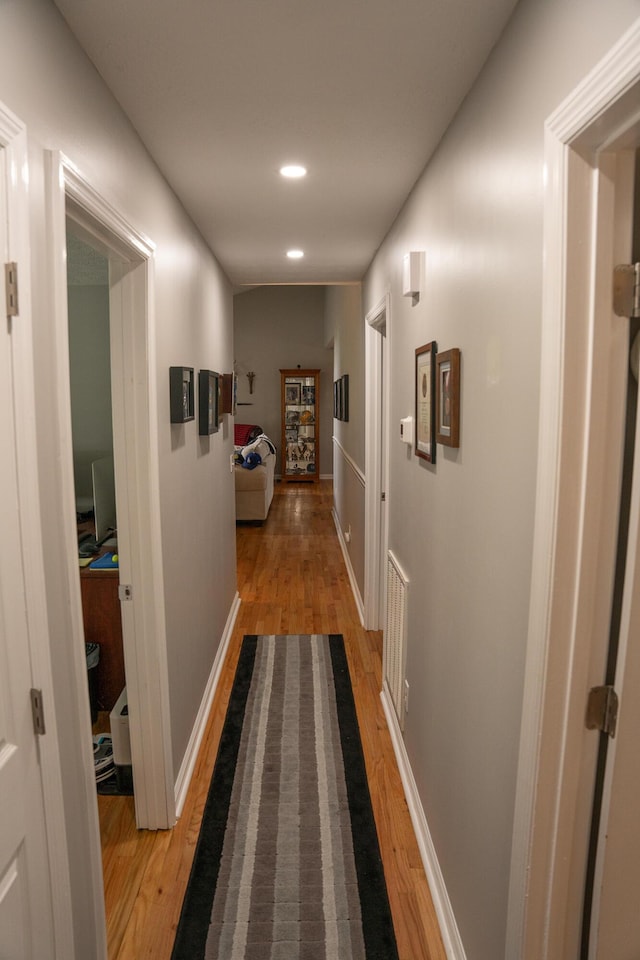 hallway featuring recessed lighting, baseboards, and light wood finished floors