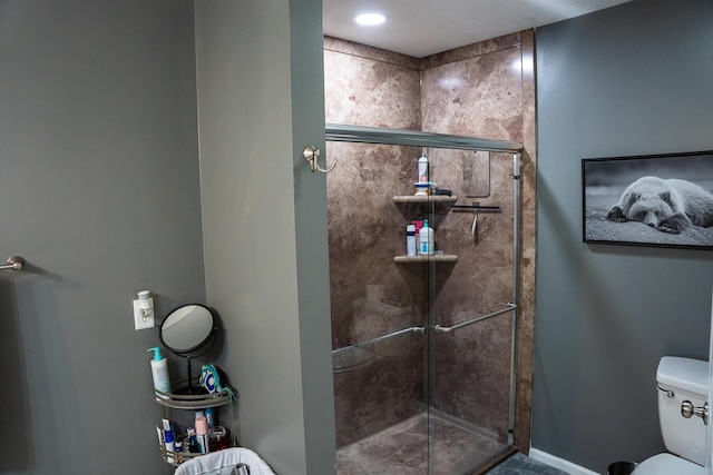 bathroom with baseboards, a stall shower, and toilet