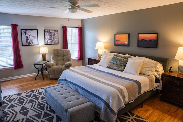 bedroom with a ceiling fan, baseboards, visible vents, and wood finished floors