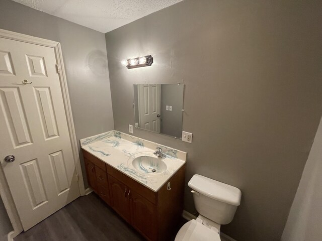 bathroom featuring toilet, a textured ceiling, wood finished floors, and vanity