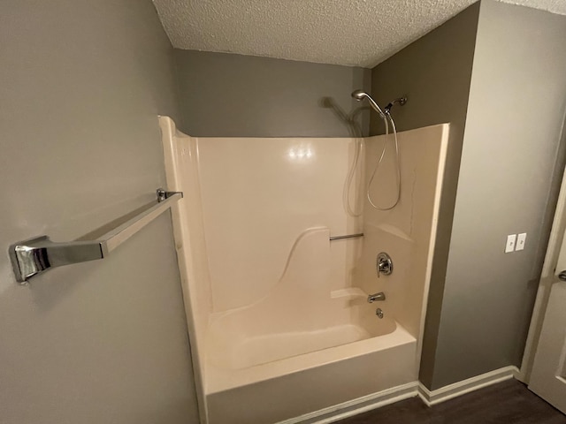 bathroom featuring baseboards, shower / tub combination, a textured ceiling, and wood finished floors
