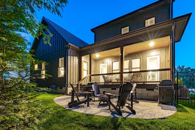 back of house featuring a fire pit, board and batten siding, a patio area, crawl space, and a lawn