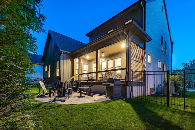 rear view of house with a lawn, fence, a patio, and board and batten siding