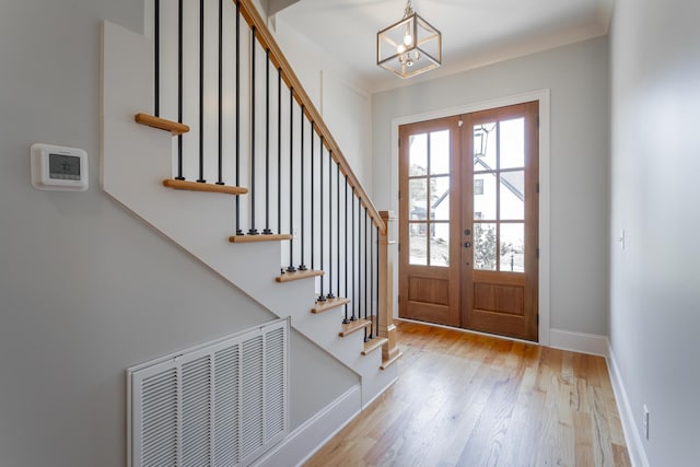 entryway with a notable chandelier, baseboards, wood finished floors, visible vents, and stairway