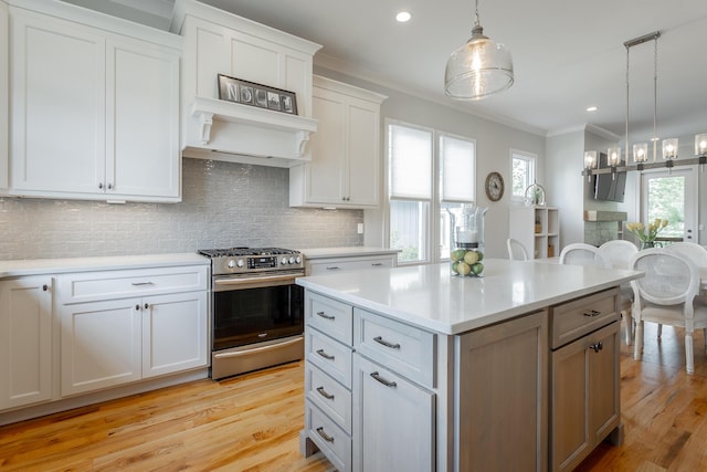 kitchen featuring stainless steel gas range, light countertops, ornamental molding, and tasteful backsplash