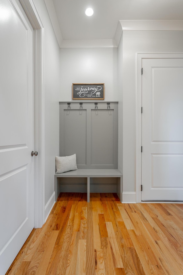 mudroom with crown molding, baseboards, and light wood-type flooring