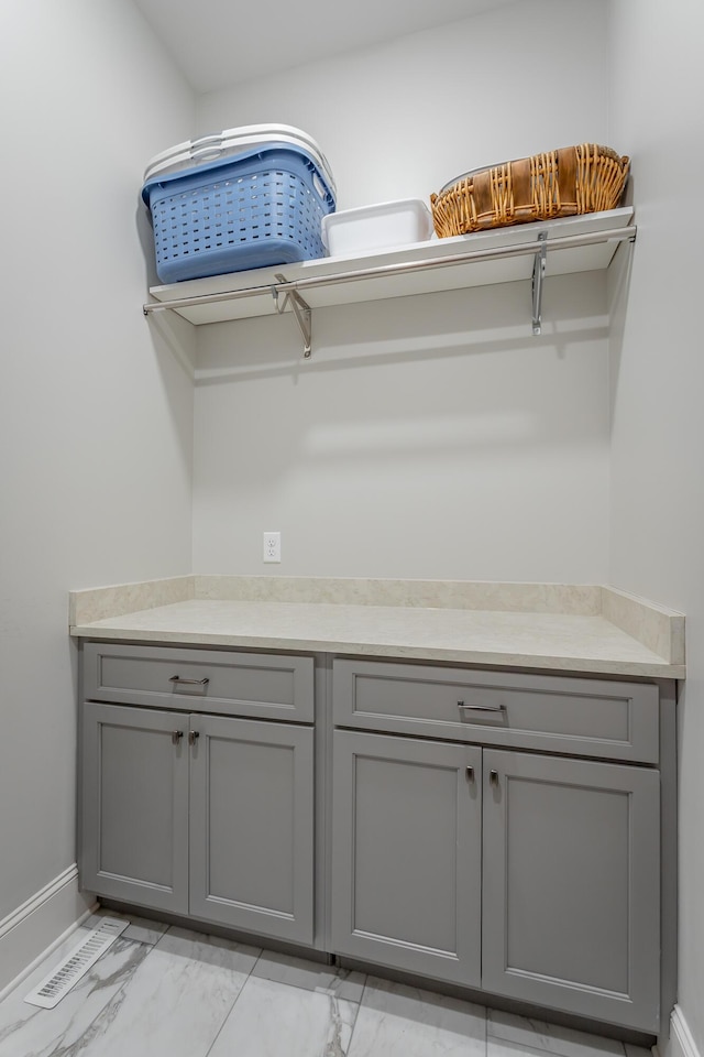 clothes washing area with baseboards and marble finish floor