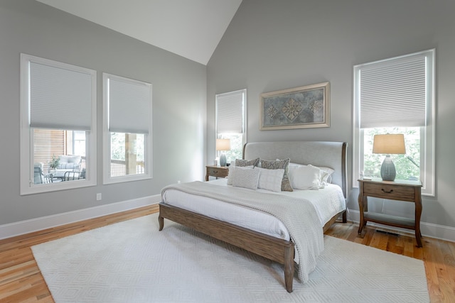 bedroom with baseboards, high vaulted ceiling, and wood finished floors