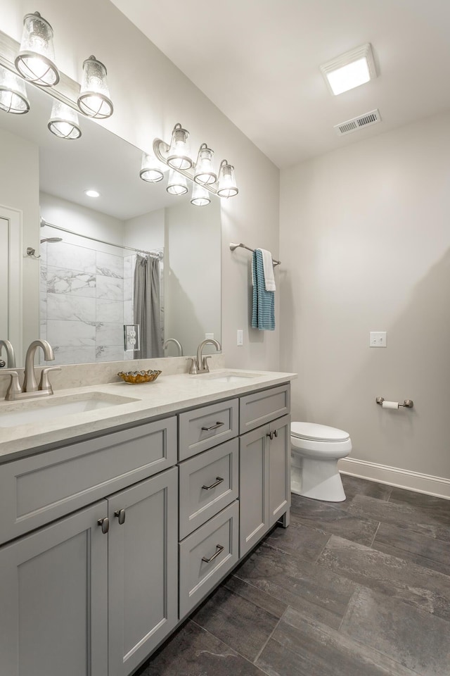 bathroom with double vanity, toilet, visible vents, and a sink
