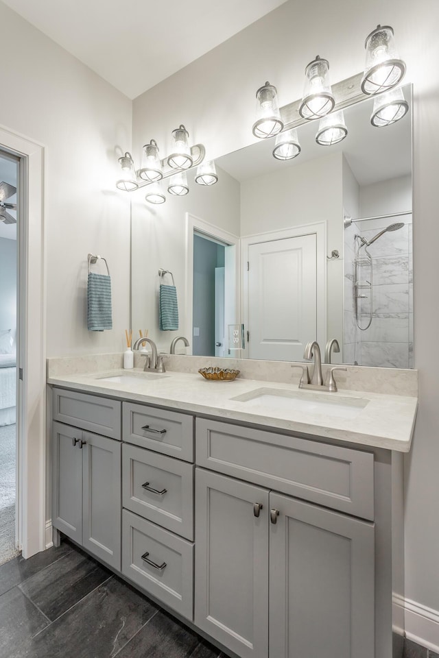 full bathroom with a sink, baseboards, double vanity, and wood finished floors