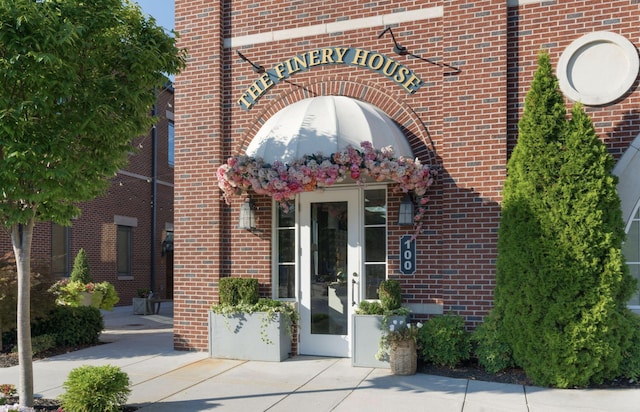 view of exterior entry featuring french doors and brick siding