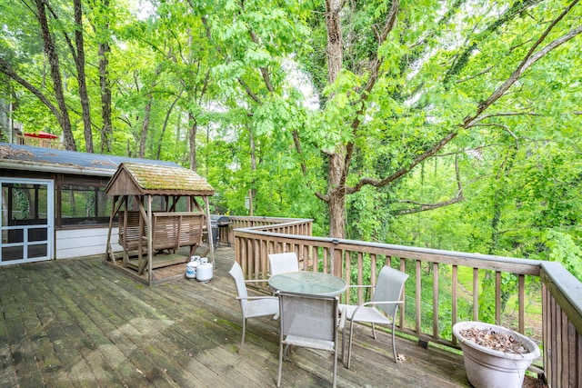 deck featuring a view of trees and outdoor dining space