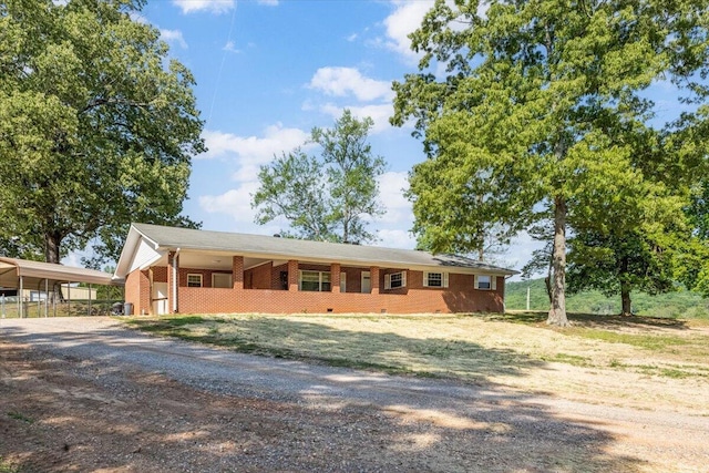view of front of property with brick siding, driveway, and a carport
