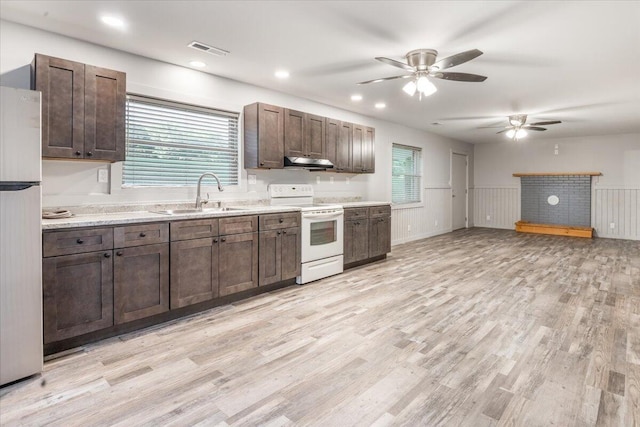 kitchen featuring a sink, white range with electric cooktop, freestanding refrigerator, under cabinet range hood, and visible vents