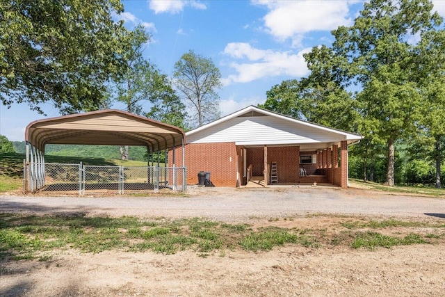 exterior space with fence, a detached carport, and dirt driveway