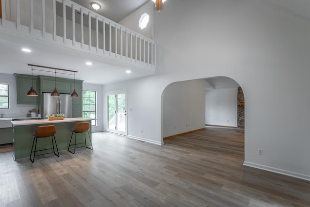 kitchen featuring arched walkways, a high ceiling, green cabinets, and freestanding refrigerator