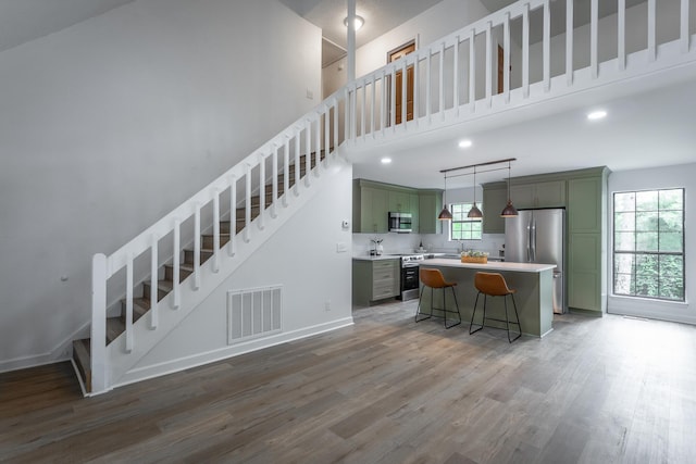 kitchen with appliances with stainless steel finishes, visible vents, wood finished floors, and green cabinets