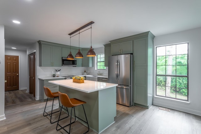 kitchen with light countertops, light wood-style flooring, a kitchen breakfast bar, and stainless steel appliances