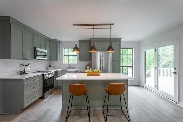 kitchen featuring a breakfast bar, light wood-style floors, a center island, light countertops, and appliances with stainless steel finishes