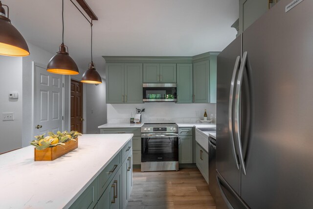 kitchen with pendant lighting, appliances with stainless steel finishes, wood finished floors, and green cabinets