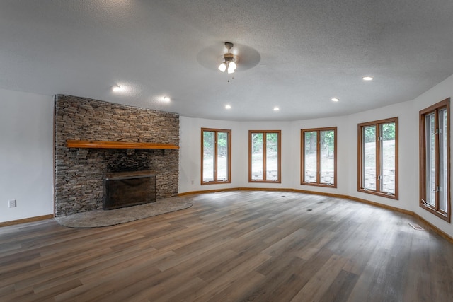 unfurnished living room featuring a fireplace, a textured ceiling, recessed lighting, baseboards, and wood finished floors