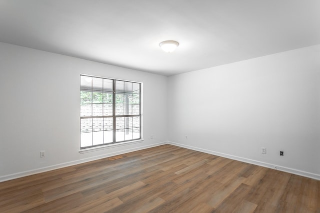 unfurnished room with baseboards and wood finished floors