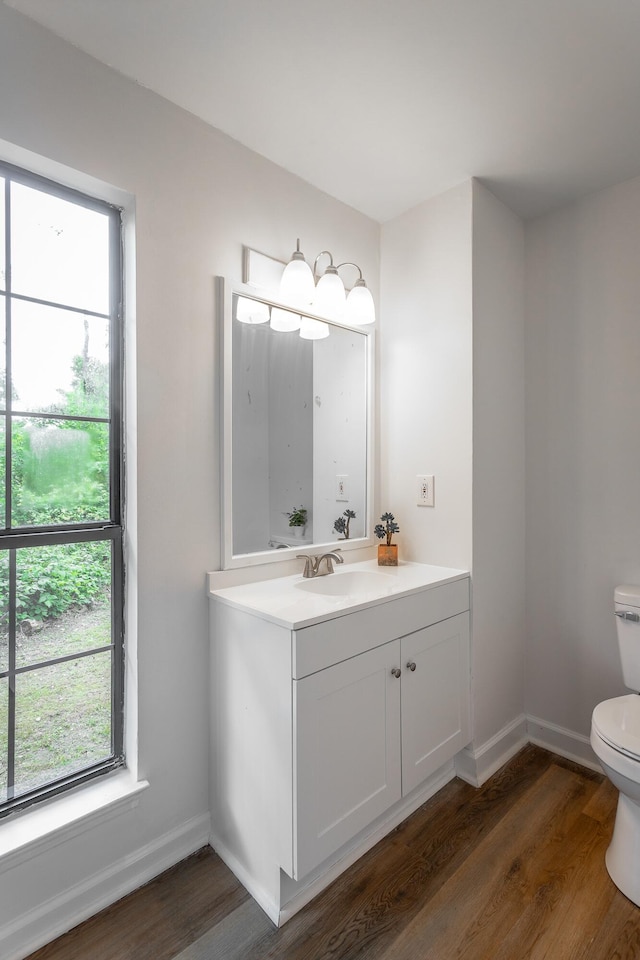 bathroom featuring vanity, baseboards, wood finished floors, and toilet