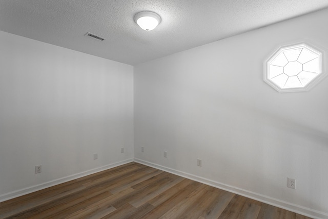spare room with baseboards, a textured ceiling, visible vents, and wood finished floors