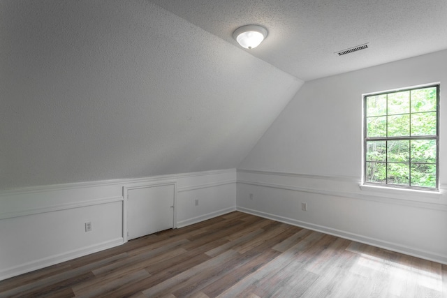 bonus room featuring a textured ceiling, baseboards, wood finished floors, lofted ceiling, and visible vents