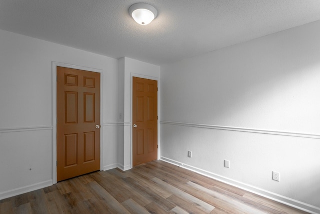 unfurnished bedroom with baseboards, a textured ceiling, and wood finished floors