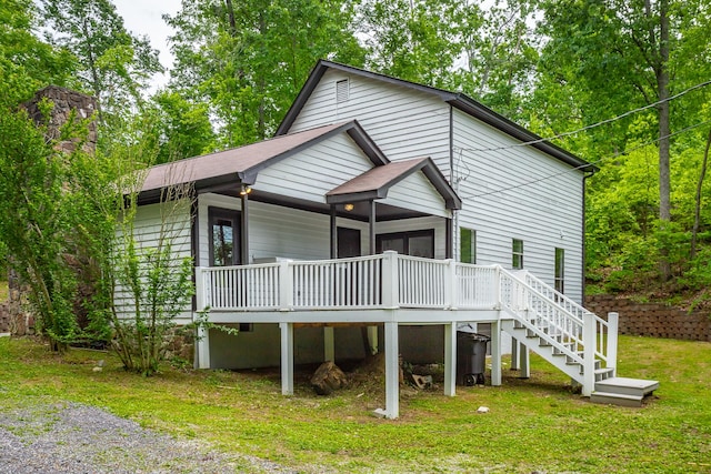 rear view of house featuring a yard, a deck, and stairs