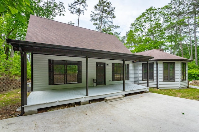 view of front of home with a porch, roof with shingles, and a patio area