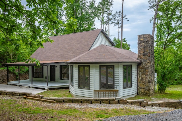 view of front of home featuring a shingled roof, a chimney, and a deck