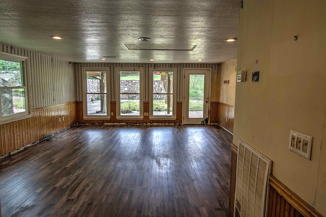 empty room with a wainscoted wall, wood finished floors, and visible vents
